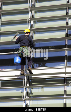 Un detergente per vetri la discesa in corda doppia di un edificio aziendale in una città del Regno Unito. Foto Stock