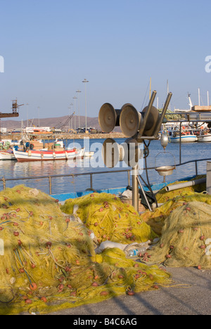 Giallo reti da pesca sul Quayside e argano di sollevamento ingranaggio con barche da pesca dietro a Lavrio porto del mar Egeo in Grecia Foto Stock