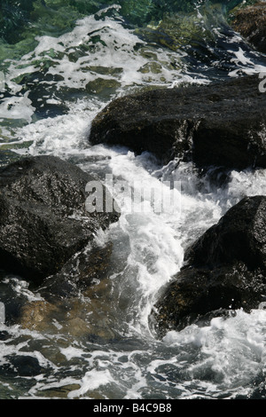 Azzurro mare di onde che si infrangono sulle rocce Foto Stock