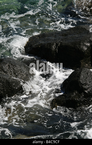 Azzurro mare di onde che si infrangono sulle rocce Foto Stock