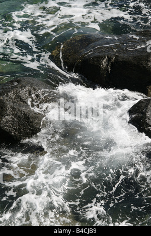 Azzurro mare di onde che si infrangono sulle rocce Foto Stock