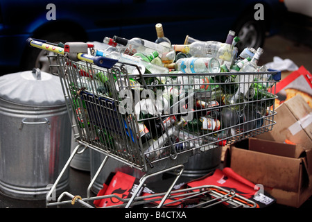 Un carrello per supermercati piena di svuotare le bottiglie e lattine in attesa di raccolta sul marciapiede fuori da un piatto in Birmingham. Foto Stock