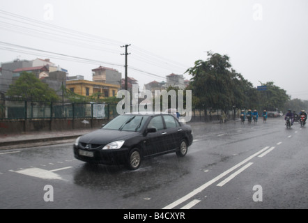 Un auto sotto la pioggia pesante per le strade di Hanoi, Vietnam Foto Stock