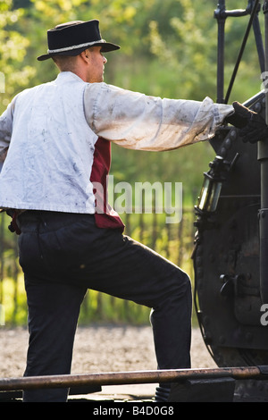 Stoker in piedi sulla pedana di una replica funzionante del Puffing Billy sul Pockerley Wagonway presso il museo Beamish, Inghilterra Foto Stock