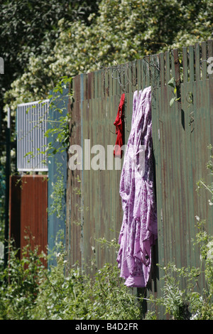 Senzatetto immigrato vestiti sulla linea di lavaggio recinzione in roma, Italia Foto Stock