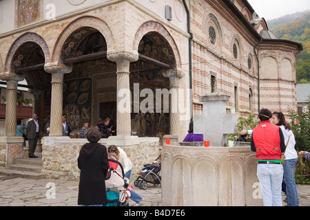 Persone fuori chiesa da fontana Santa nel 14 ° secolo monastero fortificato. Cozia Transilvania Romania Europa Foto Stock