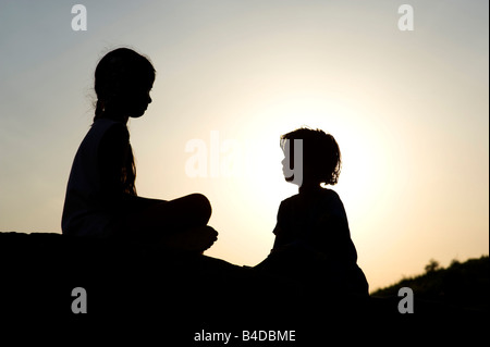 Due ragazze indiano seduto su di una roccia. India. silhouette Foto Stock