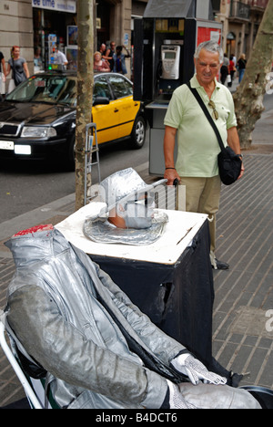 L'uomo guarda una statua umana performer di strada sulla Rambla di Barcellona, Spagna Foto Stock