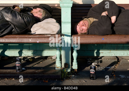 Due uomini senzatetto dormire su un banco di lavoro Foto Stock