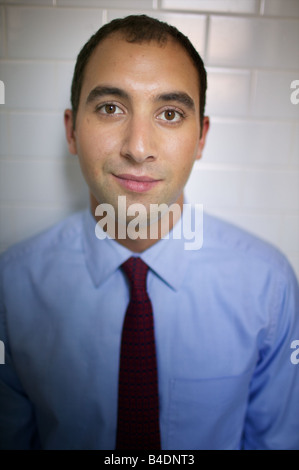 Di fronte fresca giovani indiani uomo in cravatta e camicia a collare rivolto verso il giorno dalla sua angusta New York City stanza da bagno. Assottigliamento dei capelli. Foto Stock