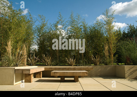 Posti a sedere in legno in moderno giardino pavimentato Foto Stock