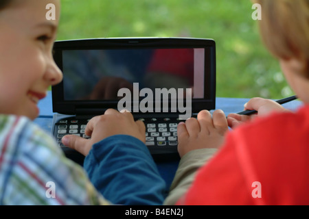I bambini di giocare e la scrittura con un PDA Foto Stock