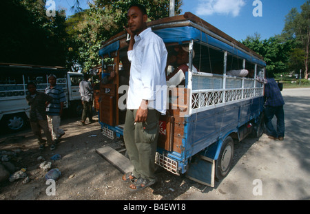 Uomo in piedi sul gradino sul retro di autobus pieno con i " commuters " presso il terminal degli autobus. Zanzibar. Foto Stock