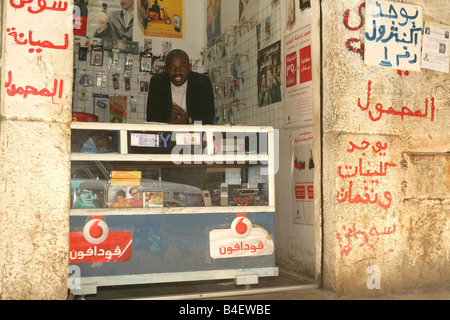Un rifugiato sudanese nella sua mobilephone accessori e officina di riparazione del Cairo in Egitto. Foto Stock