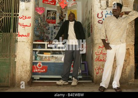 Un rifugiato sudanese di fronte al suo mobilephone accessori e officina di riparazione del Cairo in Egitto. Foto Stock