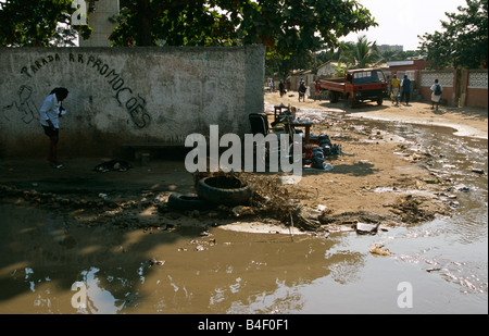 Donna che cammina con sforzo sulla strada allagata, Angola Foto Stock