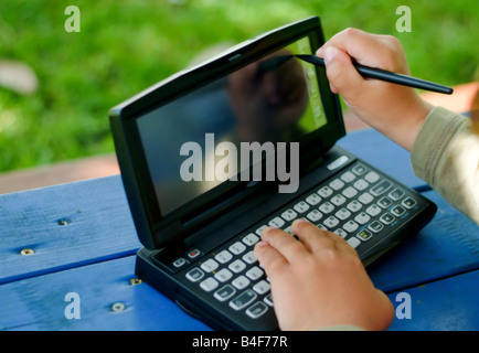 Bambino scrivendo una digitazione su un PDA Foto Stock