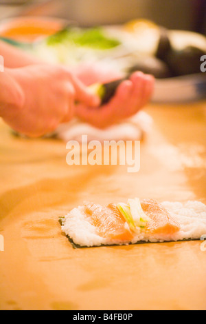 Sushi chef preparando roll collocando il riso salmone e cetriolo su alga Edomasa Ristorante Santa Barbara in California Foto Stock