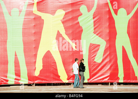 I pedoni e i banner di grandi dimensioni con sagome umane all'Manufaktura a Lodz, Polonia Foto Stock