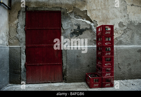 Cassette in plastica con Coca Cola bicchiere vuoto bottiglie conservate per il riciclaggio dietro un negozio con una porta rossa nel centro di Cluj Napoca Foto Stock