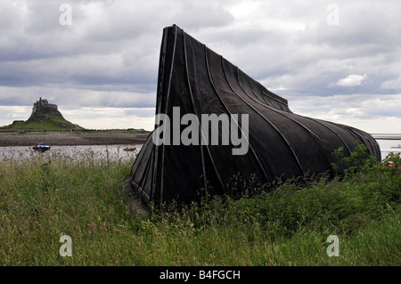 Lindisfarne Castle sull Isola Santa, Northumberland con delle nazioni unite barca capovolta scafo utilizzato come un capannone Foto Stock
