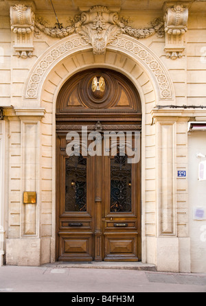 Una grande porta in legno ornata con arco decorativo in pietra e intagli a Montpellier, nel sud della Francia. Foto Stock