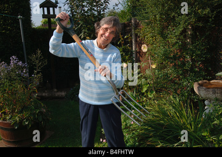 Una donna nel suo degli anni Settanta in posa con una forcella di giardino Foto Stock