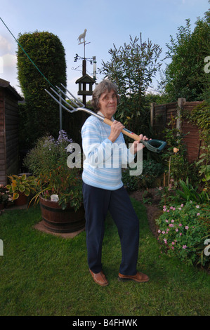 Una donna nel suo degli anni Settanta in posa con un giardino vanga Foto Stock