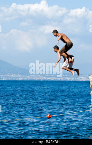 Due giovani uomini salto in mare da una scogliera Foto Stock