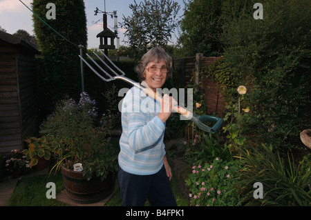 Una donna nel suo degli anni Settanta in posa con una forcella di giardino Foto Stock