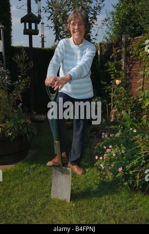 Una donna nel suo degli anni Settanta in posa con un giardino vanga Foto Stock