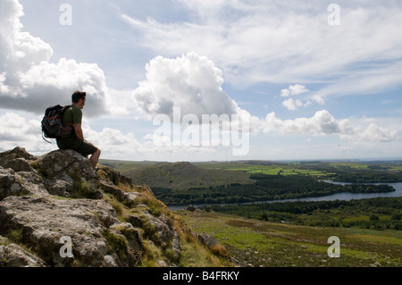 Un viandante sulla parte superiore del cuoio Tor su Dartmoor guardando fuori su serbatoio Burrator Foto Stock