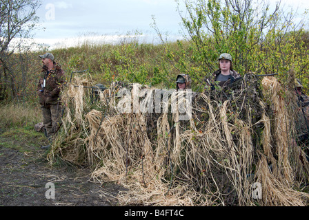 Gli adolescenti e il loro supervisore vestito in Abbigliamento camouflage in un anatra ciechi la caccia degli uccelli Foto Stock