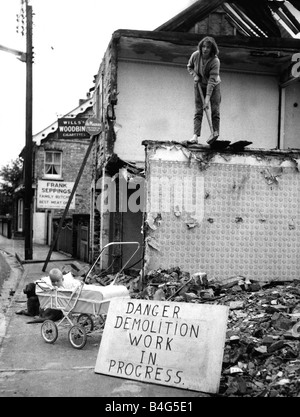 Marie Drury al lavoro di Sudbury Suffolk la demolizione di edifici suoi sei mesi figlia Michelle siede felicemente in lei la PRAM e cane Pietro resta sempre vicino al bambino segno dice Pericolo lavori di demolizione in corso dei lavori di demolizione Agosto 1961 Foto Stock