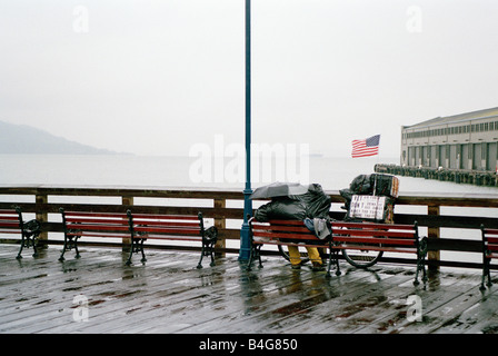 Una persona seduta su una panchina sotto la pioggia, affacciato sulla Baia di San Francisco, Stati Uniti d'America Foto Stock