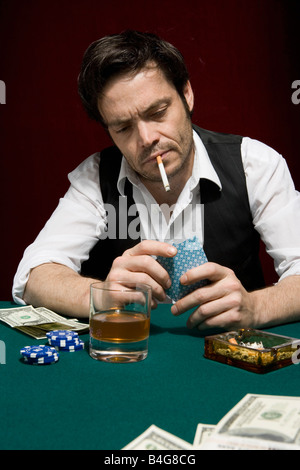 Un uomo in un high stakes poker gioco guardando la sua mano di carte Foto Stock