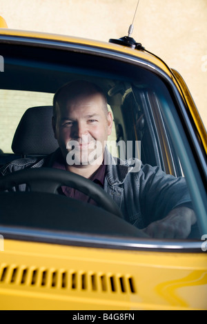 Un taxi conducente seduto nella sua auto e sorridente Foto Stock