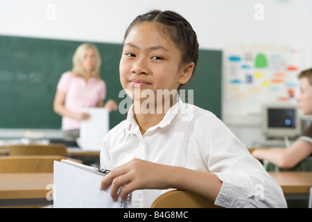Un pre-adolescenti ragazza seduta nel retro di un aula, guardando la fotocamera Foto Stock