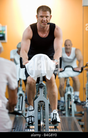 Un istruttore di fitness su una bicicletta stazionaria di insegnamento di una classe Foto Stock