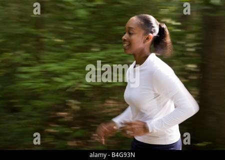 Una donna jogging attraverso il parco alberato Foto Stock