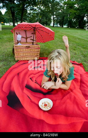 Una ragazza con una ciotola di yogurt, granola e fragole in un picnic Foto Stock