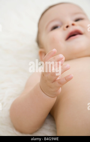 Un sorridente bambino sdraiato, il braccio sollevato Foto Stock