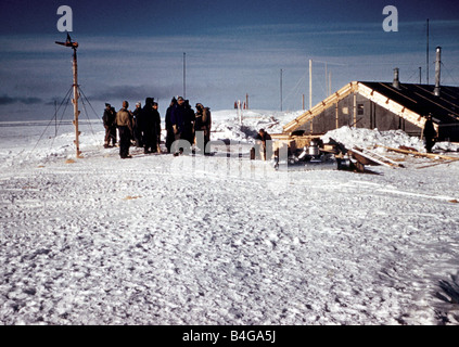 Il Trans Antarctic Expedition 1956 1958 Il camp che mostra i membri del gruppo fuori di loro log cabin esploratori soddisfare al Polo Sud i membri del team che sta tentando la prima superficie traversata dell'Antartico hanno aderito fino al Polo Sud il neozelandese Sir Edmund Hillary che ha già conquistato il Monte Everest è arrivato con il suo team 17 giorni fa presto questo pomeriggio Sir Edmund ha accolto con favore la squadra britannica guidata dal dottor coniglietto Vivian Fuchs al polo sud gli inglesi e Nuova Zelanda squadre sono membri di una comune Commonwealth Trans spedizione in Antartide ma insieme fuori dalle estremità opposte del continente Foto Stock