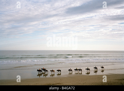 Un gruppo di persone a cavallo sulla spiaggia Foto Stock