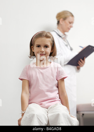 Una giovane ragazza con una femmina di pediatra in background Foto Stock