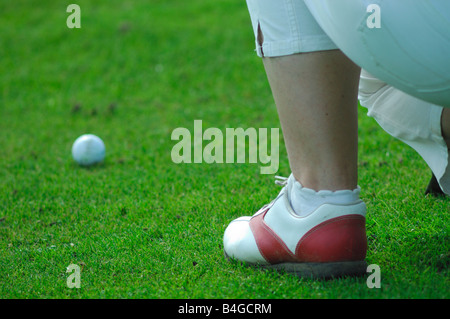 Un giovane giocatore di golf adagiandosi prima di guidare a mettere su un verde campo da golf Foto Stock