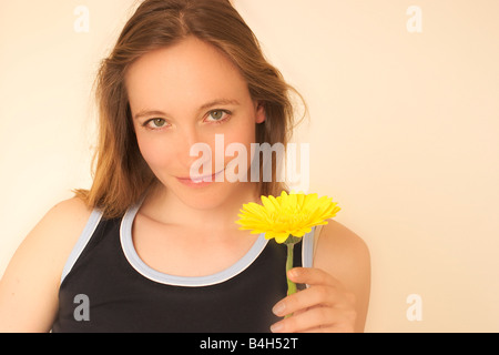Ritratto di giovane donna fiore di contenimento e sorridente Foto Stock