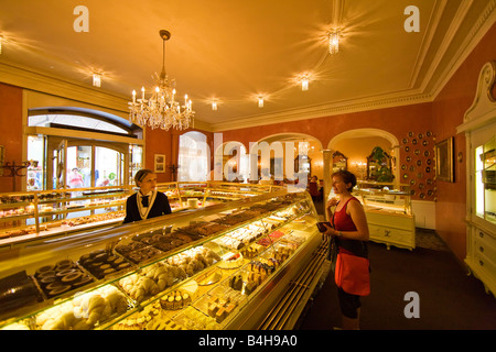 Donna che parla di addetto alle vendite in negozio di pasticceria contatore, Salzkammergut, Austria superiore, Austria Foto Stock