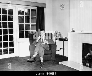 Donald Sinden attore di cinema seduto nella sua sedia a casa di fumare una sigaretta 1959 Foto Stock