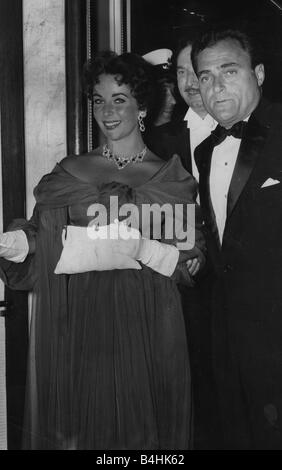 Liz Taylor con Mike Todd ex marito attrice Liz in spalla off chiffon abito da sera serata da indossare guanti protettivi e corrispondenza di collana e orecchini che trasportano pochette Luglio 1957 Foto Stock